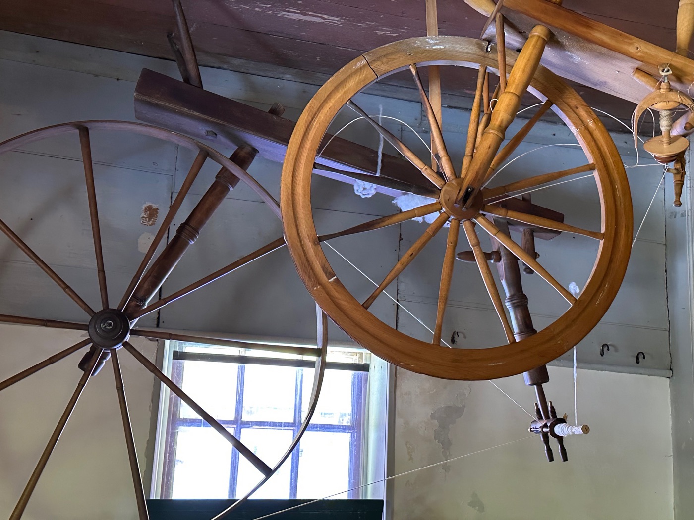 Two large Shaker spinning wheels mounted high on a wall at Canterbury Shaker Village.