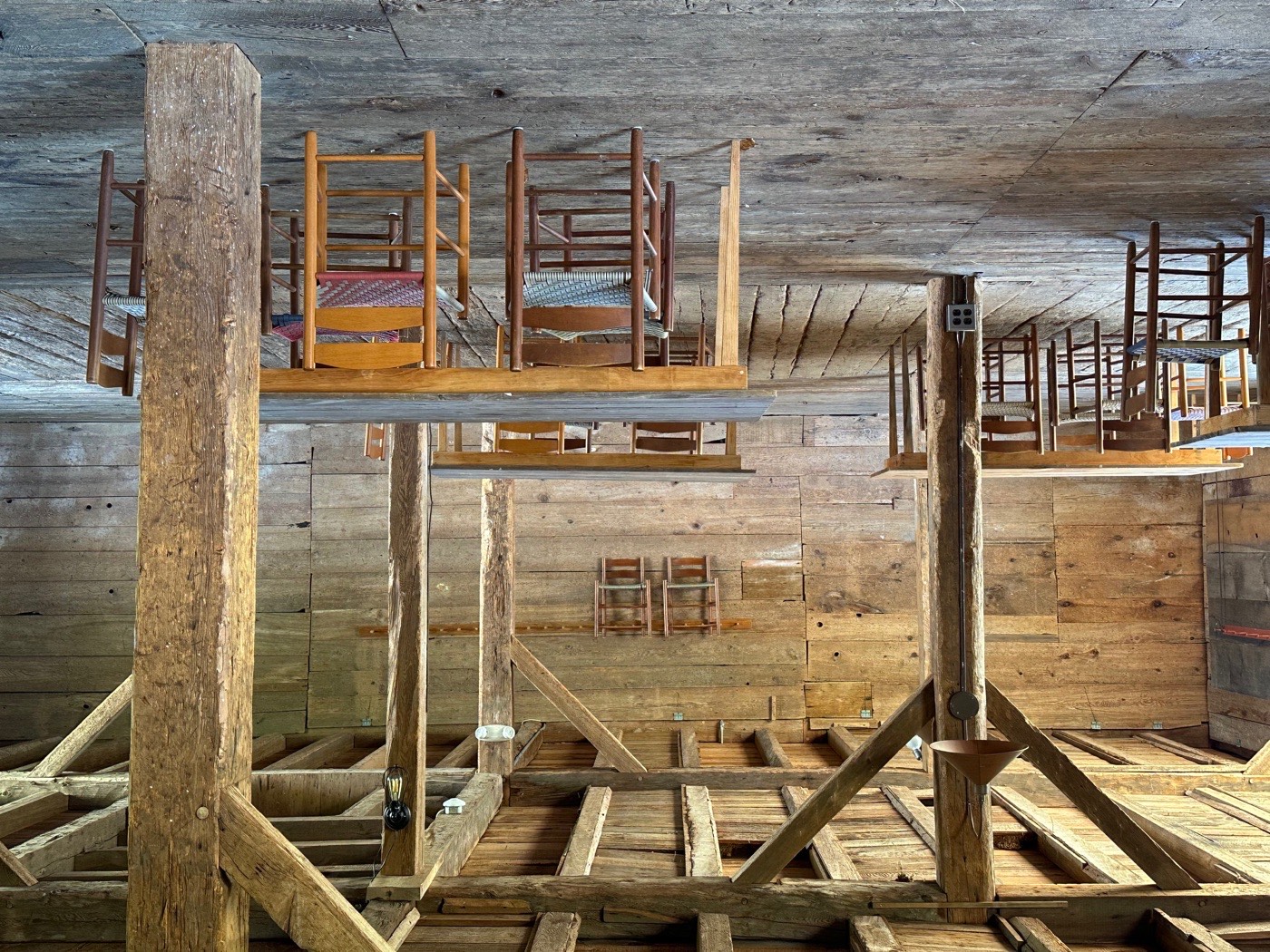 Shaker ladder-back chairs stored on a peg shelf in a post-and-beam loft at Canterbury Shaker Village.