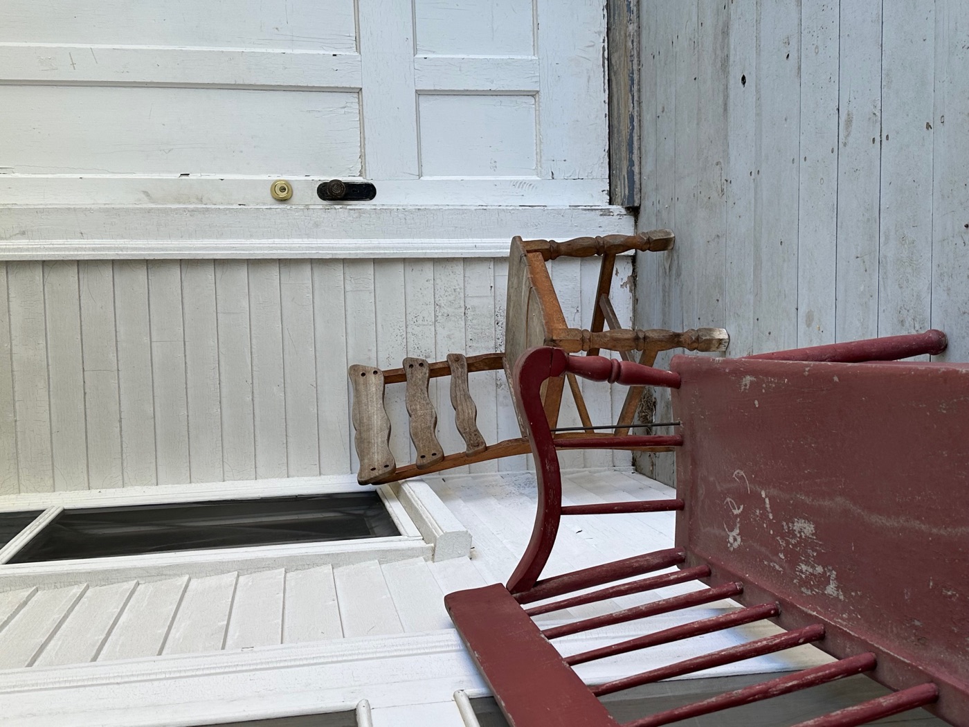 A red-painted Shaker side chair against white paneling and a peg rail.