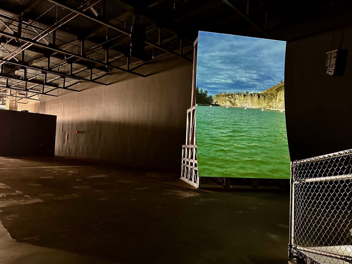 Lucy Raven's video Murderers Bar, showing a green river below rocky bluffs, on a freestanding screen at the ICA Watershed.