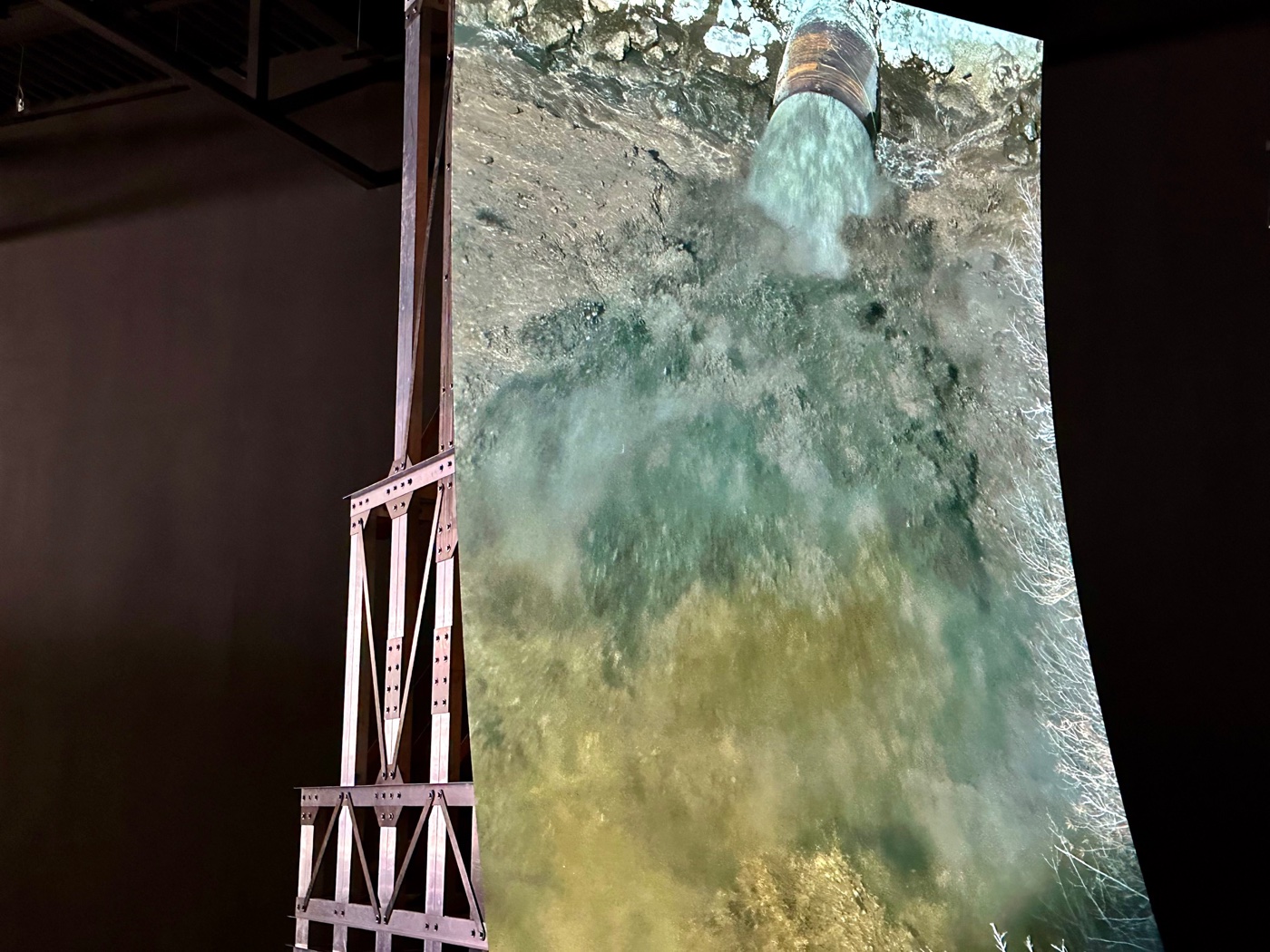 A close view of Lucy Raven's Murderers Bar at the ICA Watershed: water rushing from a pipe into a churning pool.