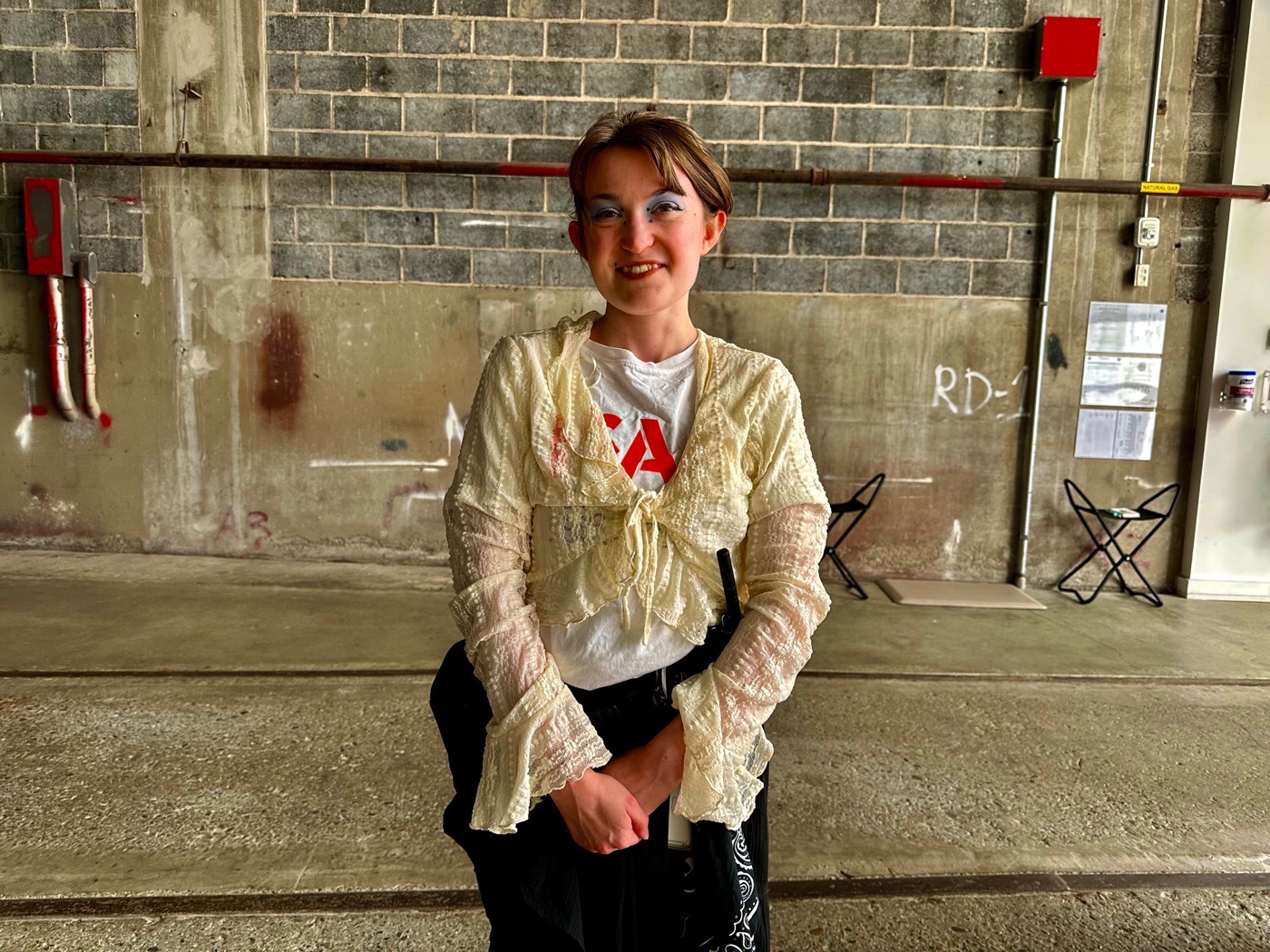 A smiling gallery attendant in front of a raw concrete block wall at the ICA Watershed in East Boston.