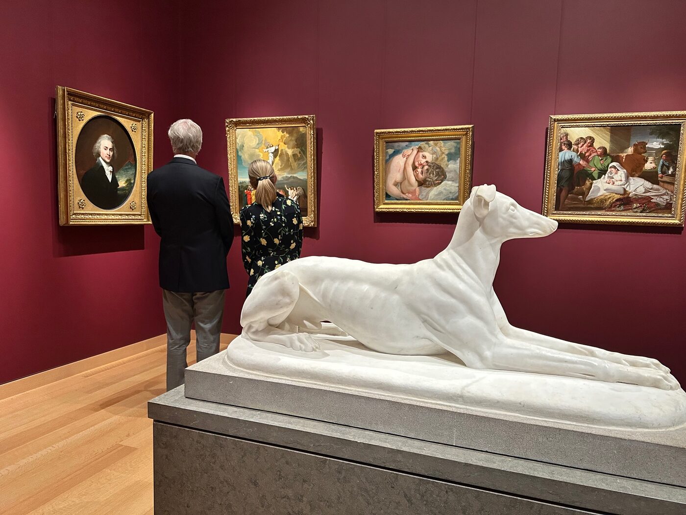 A white marble reclining sculpture on a plinth in a red-walled American art gallery at the Museum of Fine Arts, Boston.