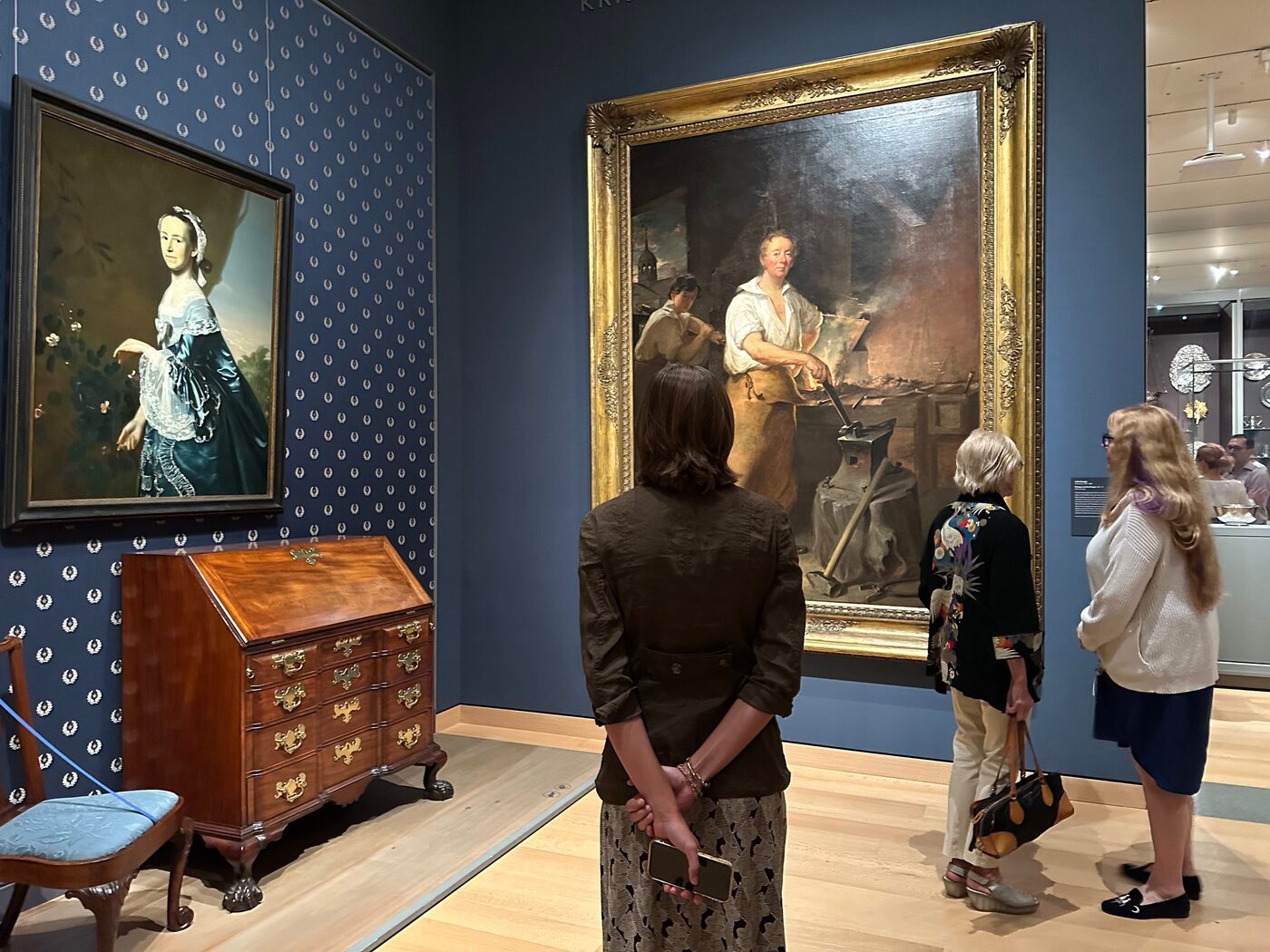 A blue-wallpapered gallery with an American chest and framed portraits at the MFA, Boston.