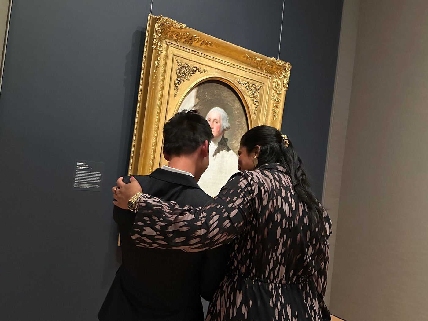 A visitor leaning in to study a newly hung painting in the reinstalled galleries at the Museum of Fine Arts, Boston.