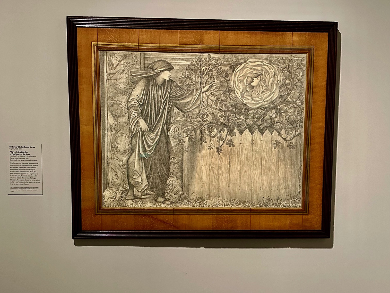 A framed drawing of a robed figure reaching toward a rose in a garden, on view during Art in Bloom at the Museum of Fine Arts, Boston.