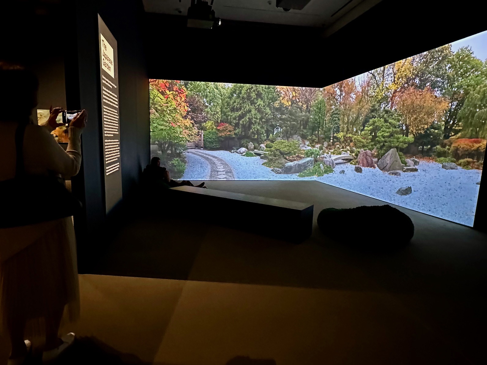 Visitors seated before a wall-sized projection of a Japanese garden during Art in Bloom at the Museum of Fine Arts, Boston.