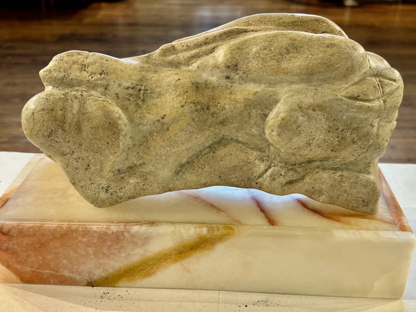 A carved abstract white stone sculpture on a marble base at the North Shore Arts Association.