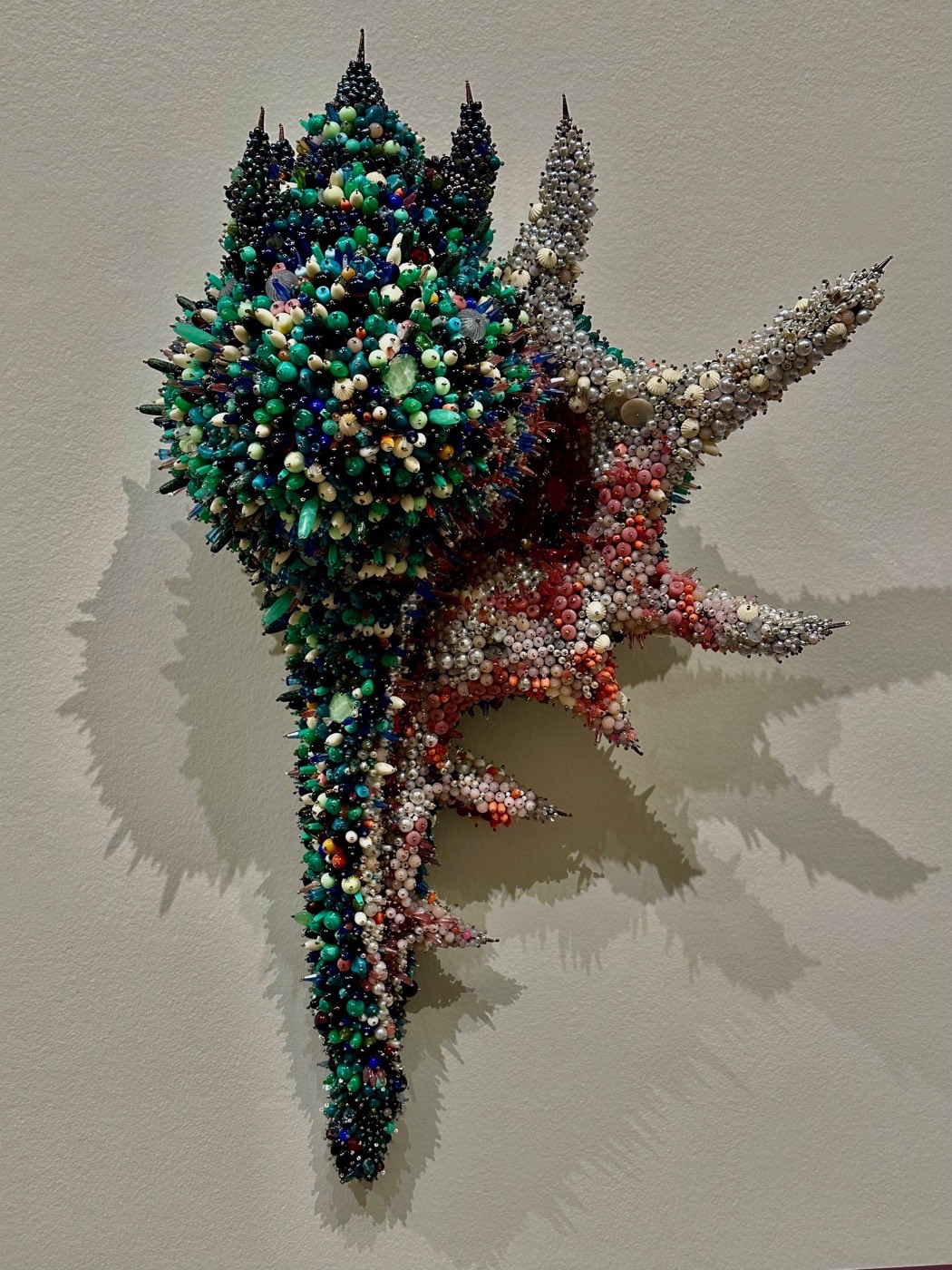 A spiky beaded wall sculpture in greens, pearls, and corals from Precious, the Value of Ornament at the Portland Museum of Art.