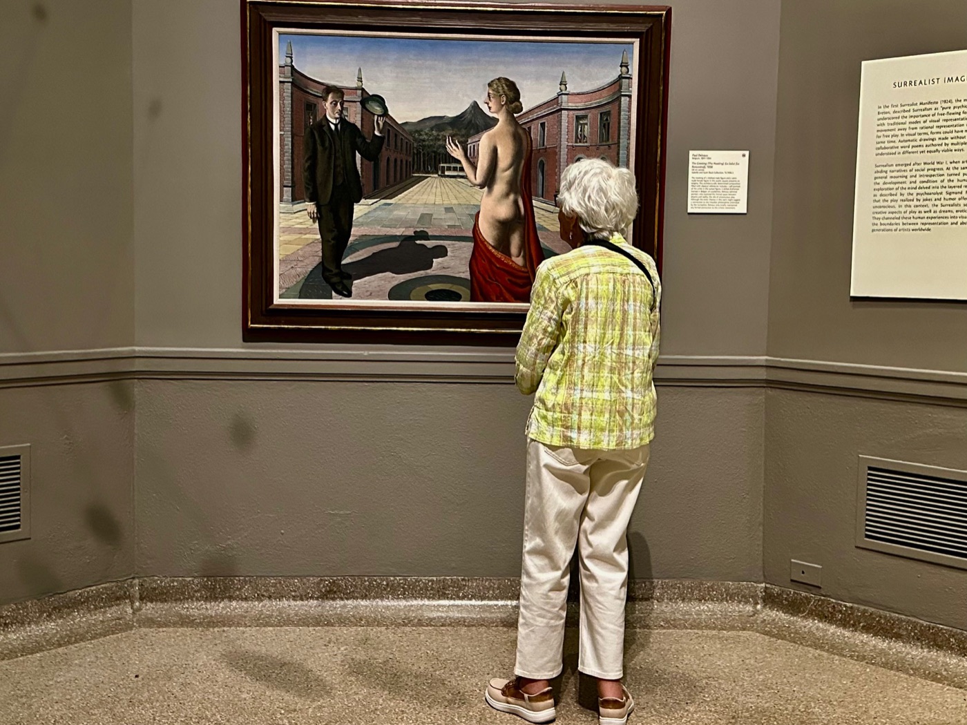 A visitor studies Paul Delvaux's painting The Greeting in a surrealist gallery at the Portland Museum of Art.