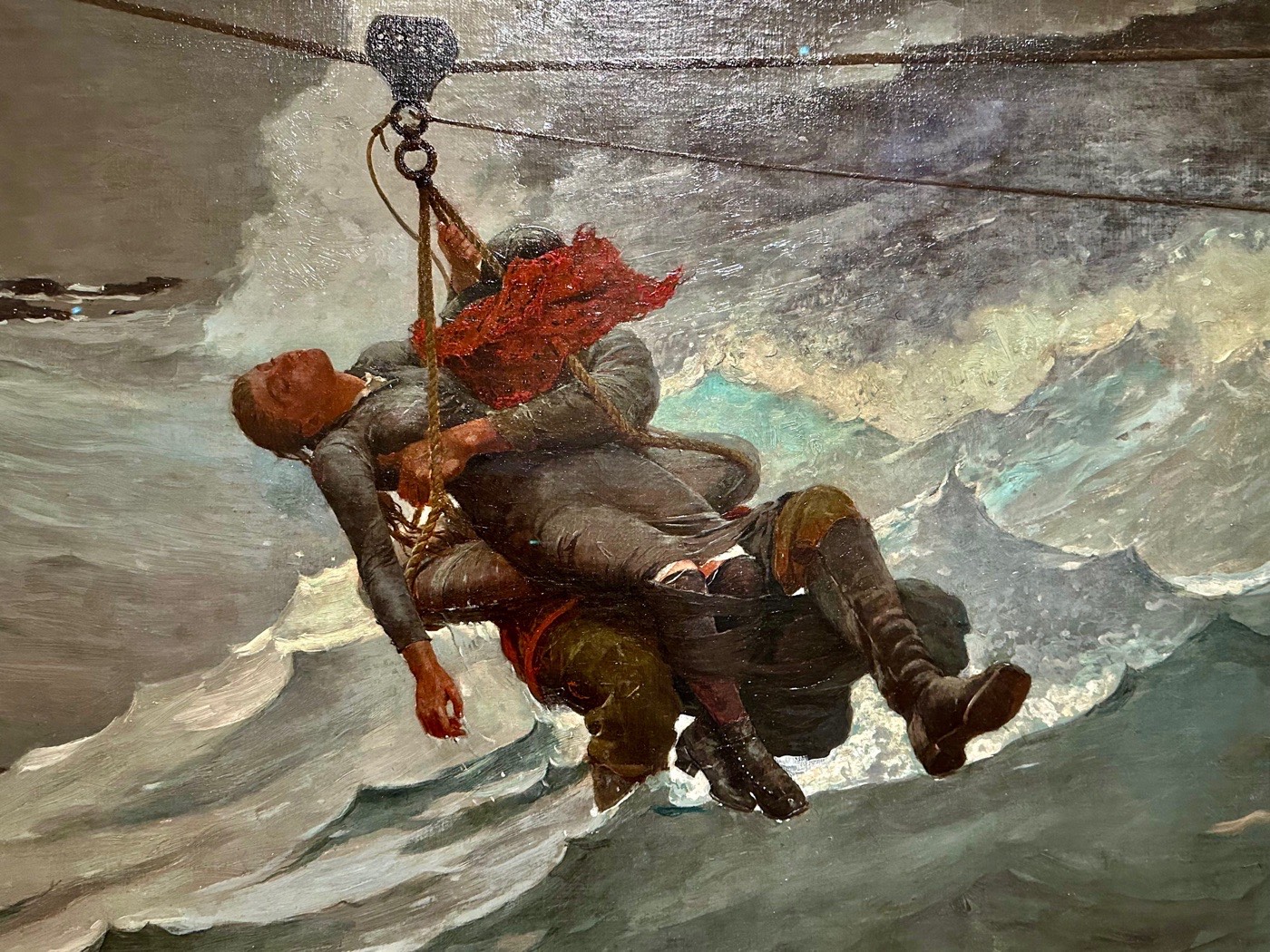 A close view of Winslow Homer's The Life Line: a rescuer carrying a woman across stormy seas on a breeches buoy.